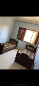 twee bedden in een kamer met een raam bij Appartement lumineux et spacieux en plein centre ville in Ouarzazate