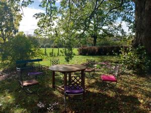 une table et des chaises dans une cour avec un arbre dans l'établissement Maison d'Adèle au hameau de Banne, 