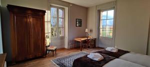 a bedroom with a bed and a desk and two windows at Maison d'Adèle au hameau de Banne 