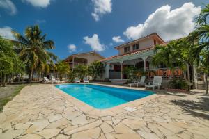 a house with a swimming pool and palm trees at Maison de 7 chambres avec piscine privee terrasse et wifi a Sainte Anne in Sainte-Anne