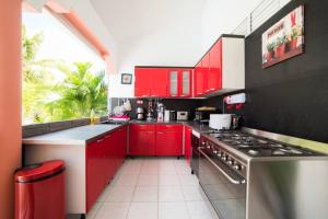 a kitchen with red cabinets and a stove top oven at Maison de 7 chambres avec piscine privee terrasse et wifi a Sainte Anne in Sainte-Anne