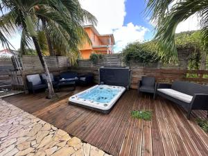 a patio with a hot tub and chairs and palm trees at Maison de 7 chambres avec piscine privee terrasse et wifi a Sainte Anne in Sainte-Anne