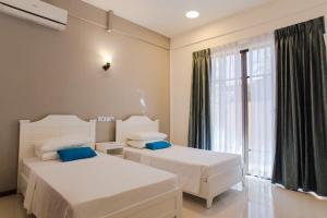 2 camas en una habitación con ventana en Riveli Retreat Mathiveri, en Mathiveri