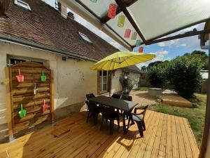 eine Terrasse mit einem Tisch und einem gelben Sonnenschirm in der Unterkunft Gîte Le temps suspendu à PEZOU 41 in Pezou