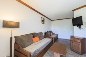 a living room with a couch and a tv at Résidence Les Bergers - maeva Home - Studio Sélection (6 personnes) 38 in LʼHuez