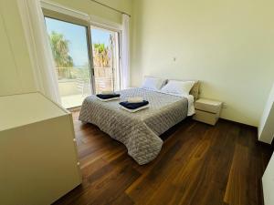 a bedroom with a bed and a large window at coral bay beach villa in Paphos City