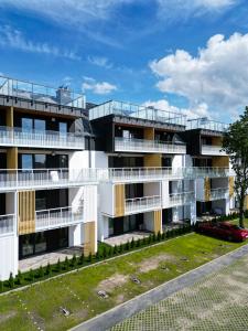 an apartment building with balconies and a car parked in front at POSESJA APARTAMENTY & SPA - Posesja Plażowa 4a III in Grzybowo