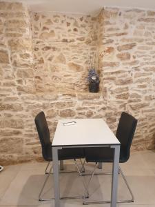 a white table and two chairs in front of a stone wall at Le segrete in Sannicandro di Bari