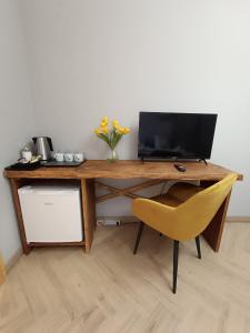 a wooden desk with a laptop and a yellow chair at Pokoje u Daniela in Miedzygorze