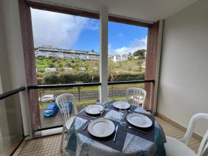 a dining room with a table and a large window at DANS LES BRAS DE NEPTUNE - Plage de TRESTRAOU - Piscine - 4 à 5 personnes in Perros-Guirec