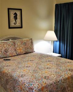 a bedroom with a bed with a blanket and a lamp at Legacy Tower II 602 in Gulfport +13 photos