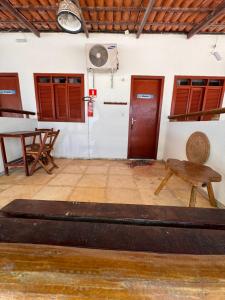 a room with a table and a bench and a fan at Pousada das Canoas in Acaraú