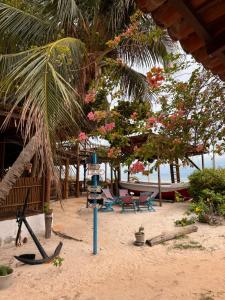 a beach with chairs chairs and a palm tree at Pousada das Canoas in Acaraú