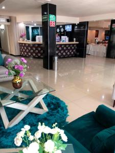 un vestíbulo con una mesa de cristal y flores sobre una alfombra azul en Hotel Francis en Culiacán