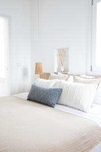 a bed with white sheets and a blue pillow on it at KAMEO, Antiparos in Antiparos