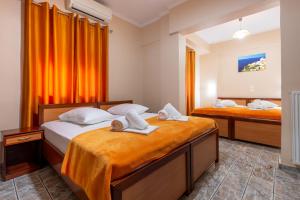 2 Betten in einem Zimmer mit orangefarbenen Vorhängen in der Unterkunft Faros I in Piräus