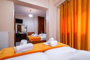 een hotelkamer met 2 bedden en een oranje gordijn bij Faros I in Piraeus