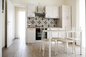 eine Küche mit weißen Schränken sowie einem Tisch und Stühlen in der Unterkunft Domus Marina - Baltico Apartment in Mondragone