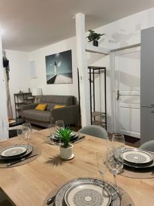 a wooden table with plates and wine glasses on it at Le Graverend T2 Charmant et central in Rennes