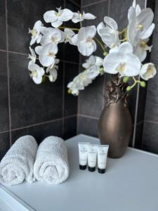 a bathroom with towels and a vase with flowers at Luxurious, Skyline View Apartment near Centre in Tallinn