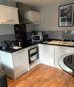 een keuken met witte kasten en een fornuis met oven bij Guest Suite Enfield in Enfield