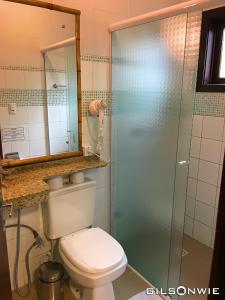 a bathroom with a toilet and a glass shower at Pousada Descanso do Rei in Praia do Rosa
