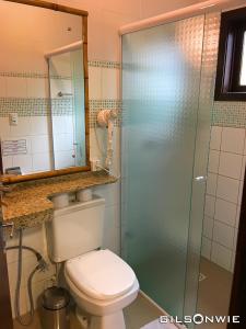 a bathroom with a toilet and a glass shower at Pousada Descanso do Rei - Vista Para o Mar & Melhor Localização da Praia do Rosa in Praia do Rosa