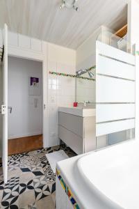 a white bathroom with a tub and a sink at Appartement 2 chambres avec garage à strasbourg in Strasbourg