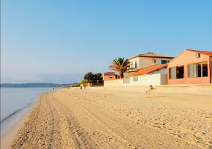 une plage de sable avec une maison et l'océan dans l'établissement Les flamants Roses la Capte • Hyères / 4pers, à Hyères