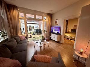 a living room with a couch and a tv at Cosy apartment in the centre of fortified town Groenlo in Groenlo