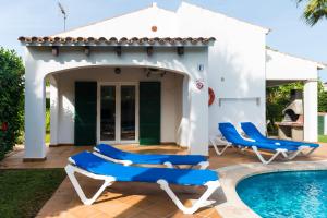 a patio with blue chairs and a swimming pool at Apartchalet villas Elvira. Villa F in Son Carrio