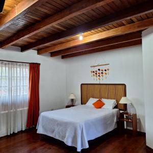 Schlafzimmer mit einem Bett mit weißer Bettwäsche und orangefarbenen Kissen in der Unterkunft Casa Wayra Cajamarca in Cajamarca
