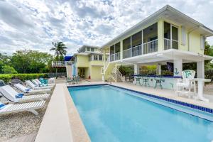 a swimming pool with chairs and a house at Luxury Key Largo Home with Guest House and Pool! in Key Largo