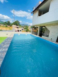 a blue swimming pool in front of a house at Sonqu Tarapoto in Tarapoto