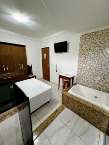 ein Hotelzimmer mit einem Bett und einer Badewanne in der Unterkunft POUSADA BRASÃO in Governador Valadares