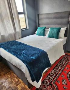 a bedroom with a large bed with a blue blanket on it at APHIROOM GUESTHOUSE in Cape Town