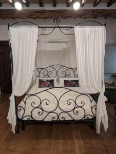 a bedroom with a canopy bed with white curtains at La Piccola Fattoria nella Campagna Umbra in Badiola