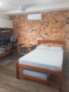 ein Schlafzimmer mit einem Bett und einer Ziegelwand in der Unterkunft APART STUDIOS PONTAL in Ilhéus