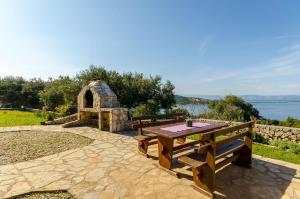 a picnic table and a stone oven with a view of the water at Apartments Mrvelj in Gdinj