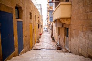un vicolo vuoto tra due edifici con porte blu di Blue Door Valletta a La Valletta