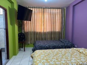 - une chambre avec des murs violets et verts et un lit dans l'établissement Ñariwalac, à Piura