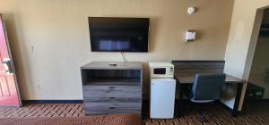 a room with a desk with a computer and a tv at Super 7 Inn in Midland