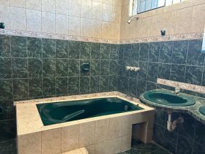 a bathroom with a green tub and a sink at Ñariwalac in Piura