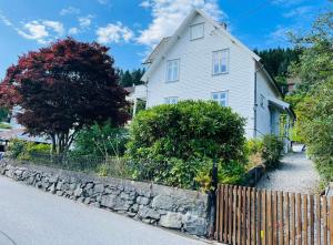 une maison blanche avec une clôture devant elle dans l'établissement Brand new flat, parking!, à Bergen