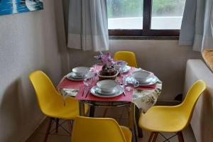 a dining room table with yellow chairs and a red table cloth at Apartamento à beira-mar. Beachfront apartment in São Gonçalo do Amarante
