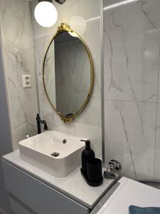 ein Badezimmer mit einem weißen Waschbecken und einem Spiegel in der Unterkunft Brand new flat, parking! in Bergen
