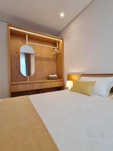 - une chambre avec un grand lit blanc et un miroir dans l'établissement Gjiri i Lalzit - San Pietro - Savita Premium Apartments, à Durrës
