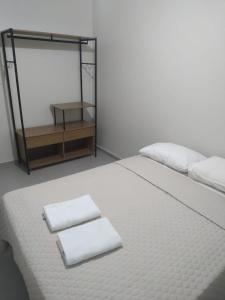 a white bed with two towels on top of it at My House Hospedagem in Santo Ângelo