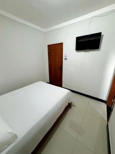 1 dormitorio con 1 cama y TV en la pared en POUSADA BRASÃO, en Governador Valadares