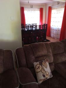 sala de estar con sofá marrón y cortinas rojas en Annex, en Kakamega